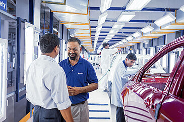 A Leadec employee talking to the customer in the paint shop of an automotive factory.